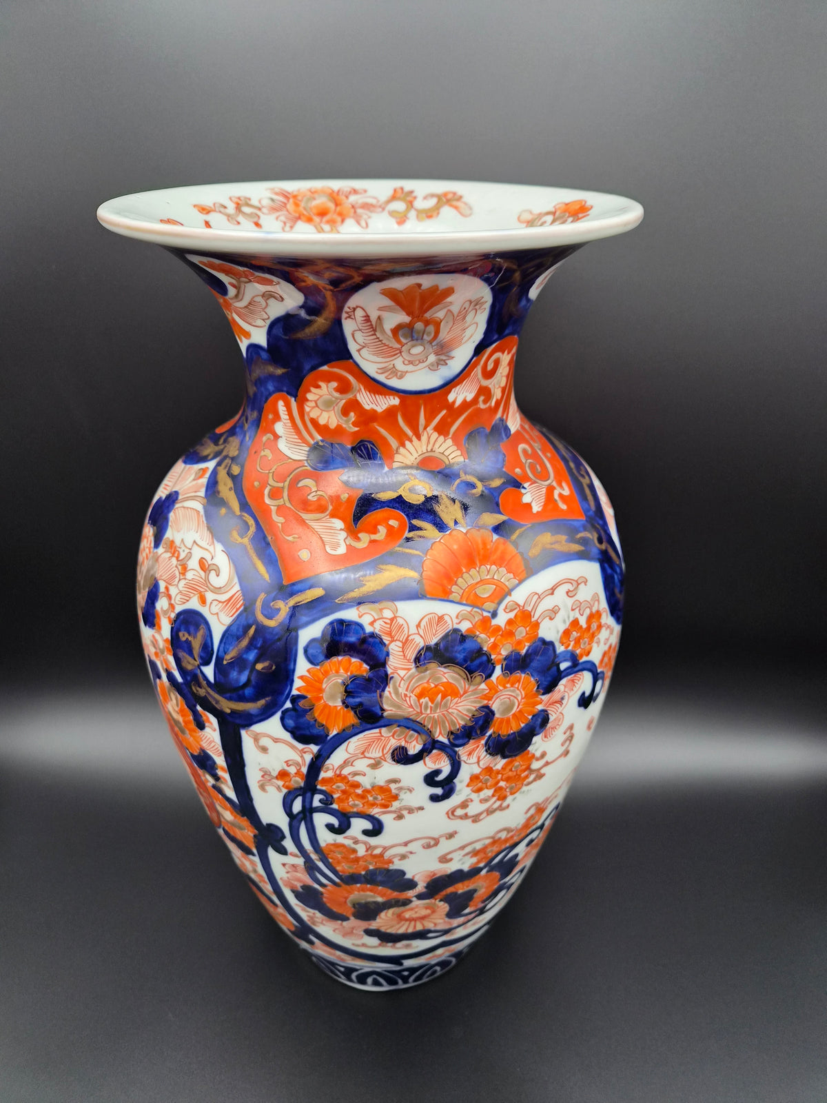 Porseleinen vaas met ronde voet en brede buik, oranje en blauwe bloemornamenten.
