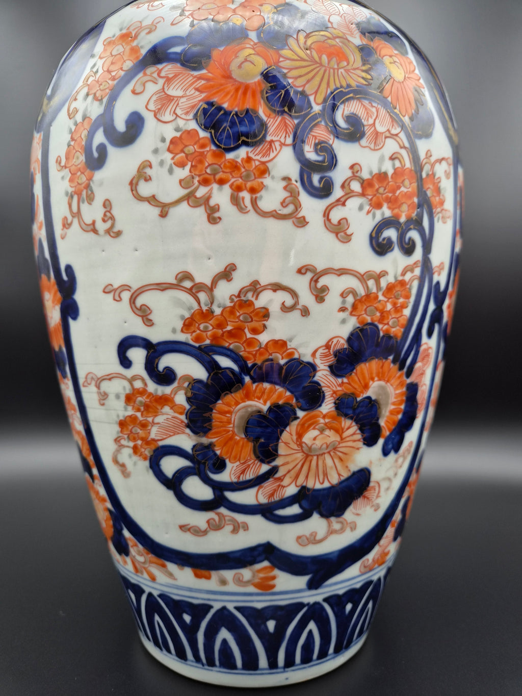 Porseleinen vaas met rijke blauw-oranje decoratie over buik en hoge smalle hals.