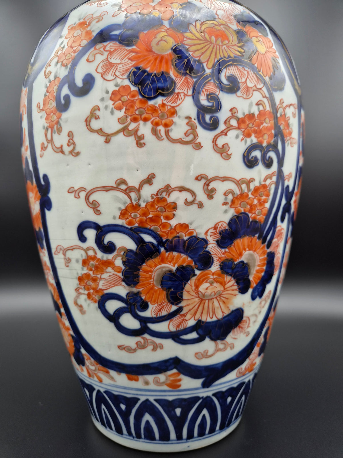 Porseleinen vaas met rijke blauw-oranje decoratie over buik en hoge smalle hals.