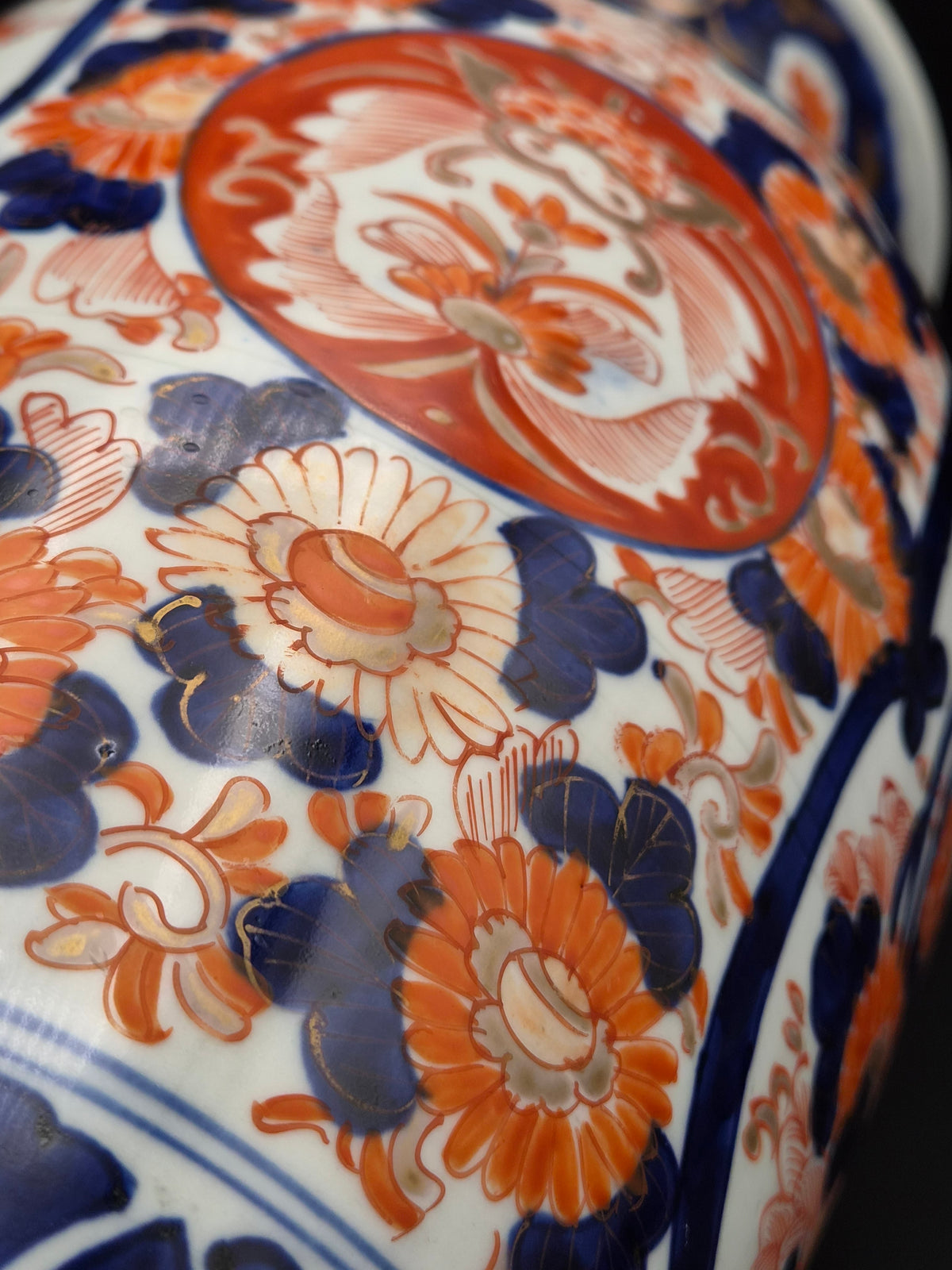 Porseleinen vaas met close-up bloemmotief en donkere blauwe krullen op witte ondergrond.