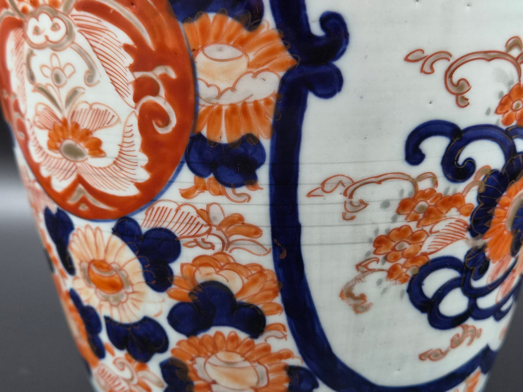 Porseleinen vaas met blauw-oranje bloem- en ornamentdecor op witte ondergrond.