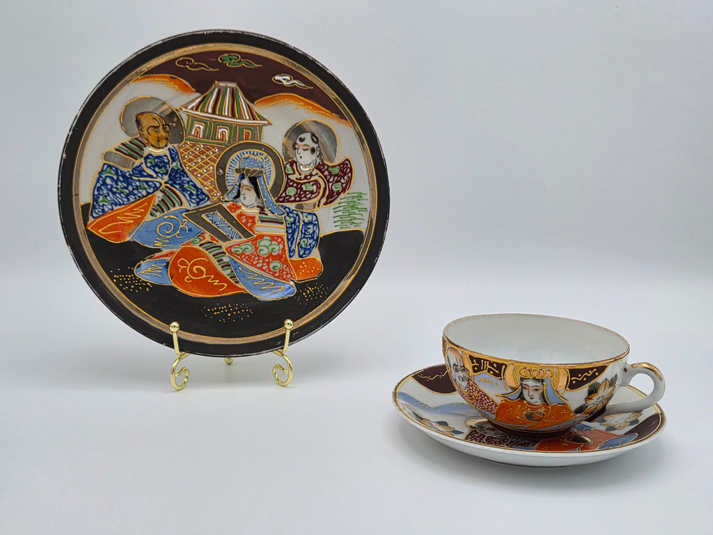Theekop en schotel met handbeschilderde figuren, plus decoratieve bordplaat op standaard