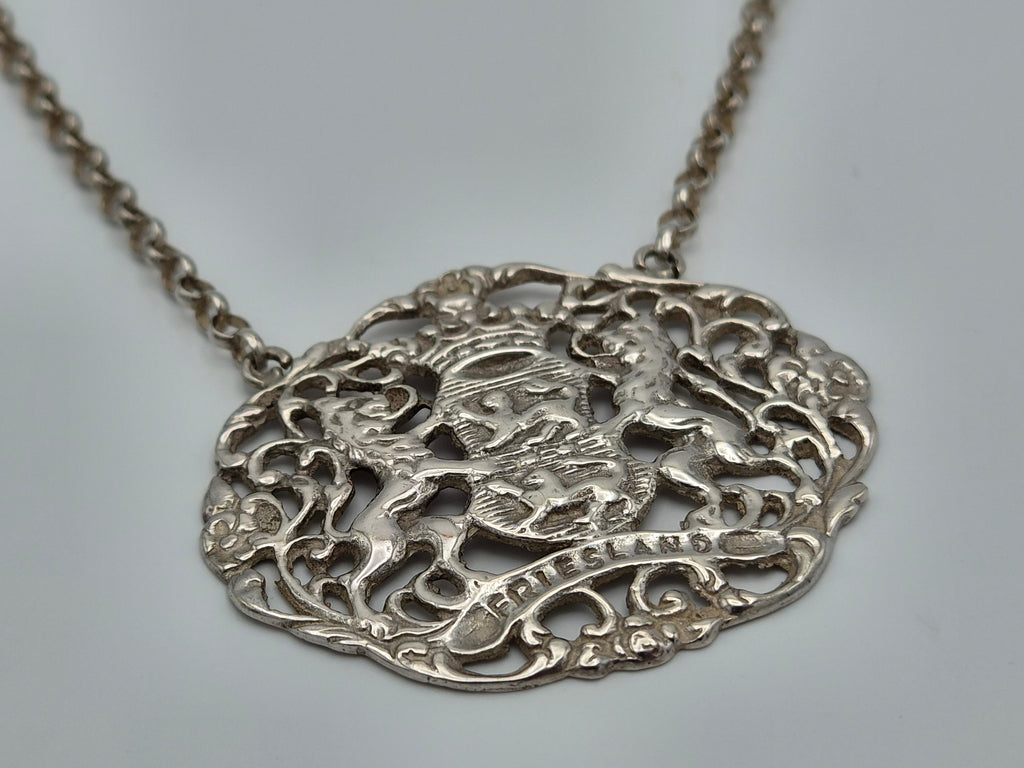 Zilveren ketting met close-up van ovale, gedetailleerde opengewerkte hanger