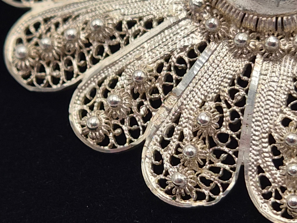 Detail van zilveren filigraanbloem met open patronen en kleine parelvormige steentjes
